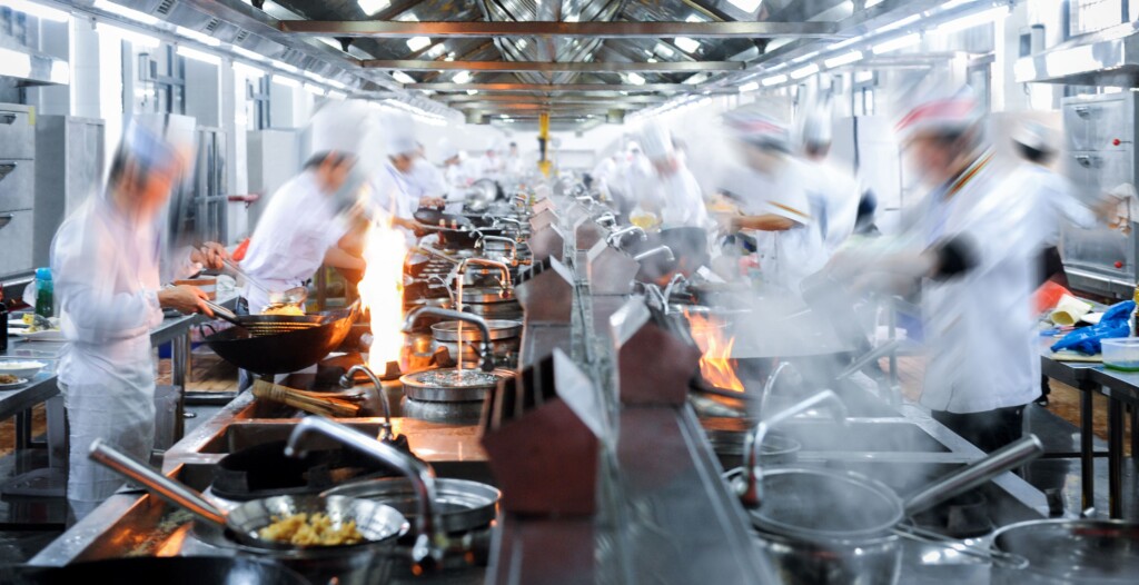 Cucina professionale in attività con operatori al lavoro, ambiente HACCP e controllo sicurezza alimentare